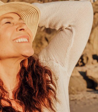 Joyful woman in a sun hat enjoying the sunshine by the sea