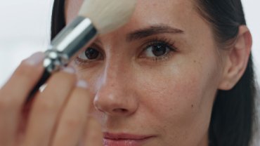 Pov morning girl makeup routine indoors. Portrait woman applying powder alone